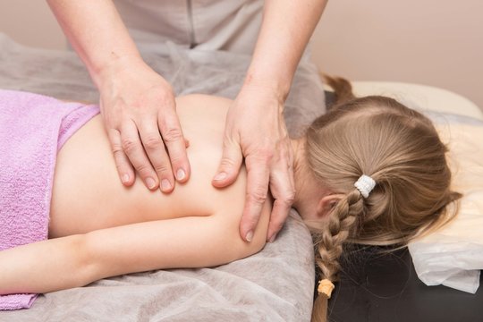 the masseur gives the child a back massage