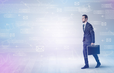 Handsome businessman walking in suit with briefcase on his hand and online communication concept around

