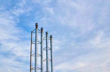 Four pipes from the boiler room against the blue sky with clouds.