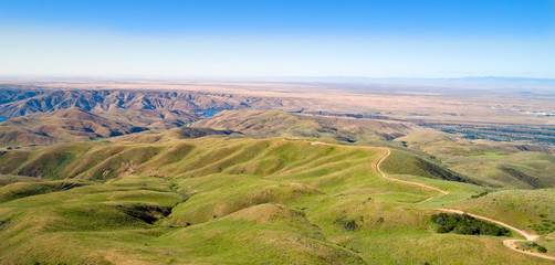 Naklejka premium Winding dirt road in the foothills over Luck Peak reservoir in summer