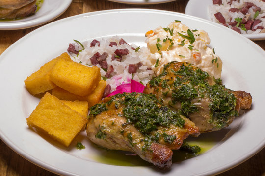 Galeto ao molho de ervas com polenta, arroz carreteiro e salada de batata