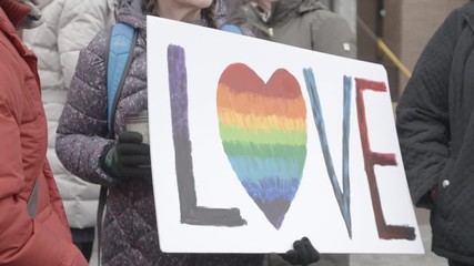 Close-up of a protest sign that says 'love' with rainbow colours