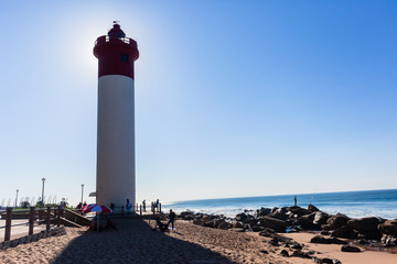 Fototapeta na wymiar Beach Ocean Lighthouse Backlight People
