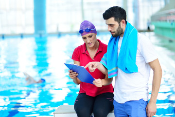 Swimmer and coach discussing by the pool at leisure center