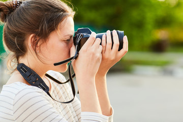 young girl taking pictures on camera in a summer Park at sunset