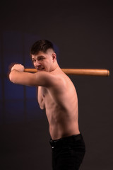 View of a muscled man on a black background  with  baseball bat