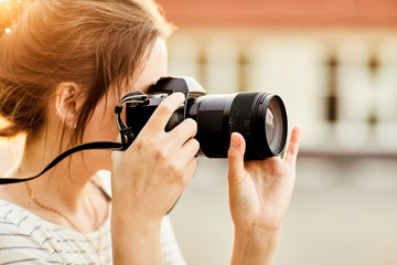 young girl taking pictures on camera in a summer Park at sunset