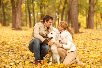 Fototapeta premium Family portrait of young man and woman with his dog Labrador in an autumn park.