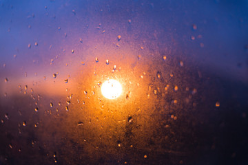 Blurred texture. Sunset after the rain through the glass with droplets.
