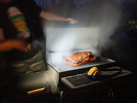 Der ge&ouml;ffnete Smoker Grill gibt den Blick auf die langsam garende Schweineschulter frei