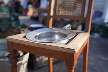 Old brown chair with a bowl on it to be used as a toilet