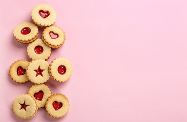 Traditional Christmas Linzer cookies with sweet jam on color background, top view