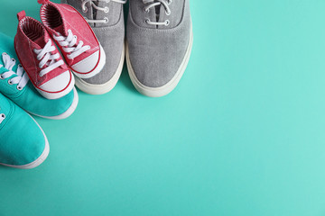 Small and big shoes on color background, top view