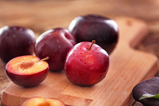 Ripe juicy plums on wooden board