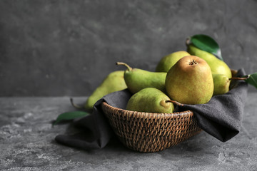 Delicious ripe pears in wicker basket on table