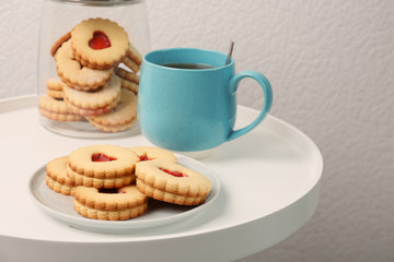 Traditional Christmas Linzer cookies with sweet jam and cup of tea on table