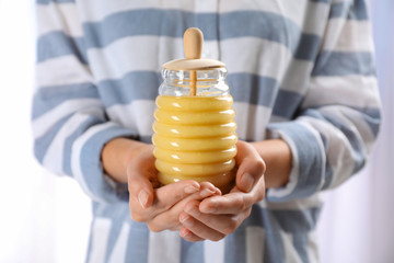 Woman holding glass jar with fresh sweet honey, closeup