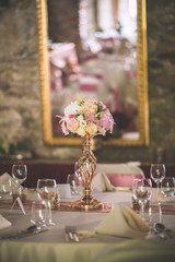 wedding table with exclusive floral arrangement prepared for reception, wedding or event centerpiece in rose gold colour