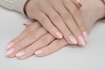 Hands with manicured nails covered with pink nail polish on fur background