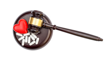 Gavel with red heart and pills on white. Medical law concept. Top view.