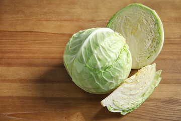 Whole and sliced cabbages on wooden table