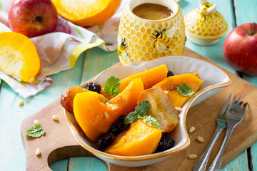 Pumpkin baked with apples, prunes and spices in a bowl on a wooden table. Diet menu. The concept of healthy eating.