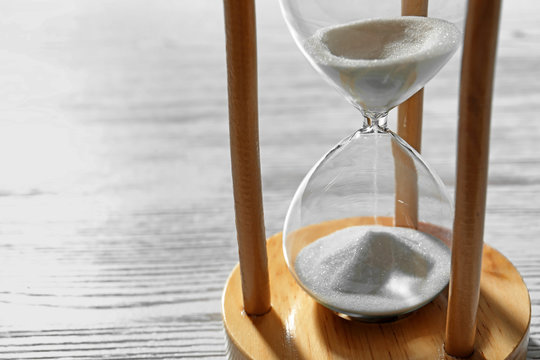 Hourglass with flowing sand on wooden background. Time management
