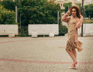 A romantic girl in the city wearing a dress and a sweater of warm colors, her hair develops in the...