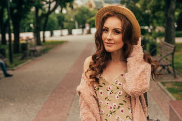 A romantic girl in the city wearing a dress and a sweater of warm colors, her hair develops in the...
