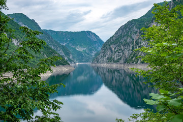 Naklejka na ściany i meble An unusual mountain lake with turquoise water is located in a canyon among the high mountains.