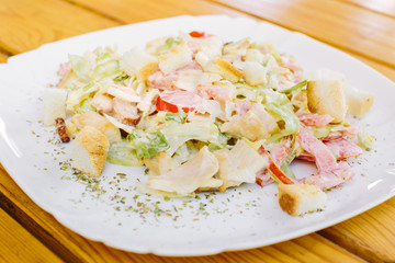Chicken salad with tomatoes, arugula and bread croutons in the white bowl