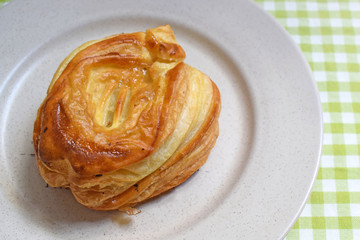 brown bun with apples on a plate. Puff pastry with fruit filling. Homemade pastries.