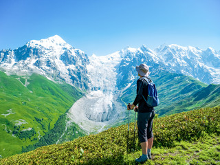 Fototapeta na wymiar Tourist with a backpack in front of Glacier in Caucasus mountains. Svaneti region, Georgia
