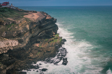 Fototapeta premium View of beach with large waves near Atlantic coast. Large waves of turquoise water crushing on a beach Praia Grande, Sintra, Portugal. Travel concept. Vintage effect. 