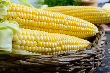 Raw sugar corn, sea salt, spices, herbs, butter on a dark wooden table. Close-up.