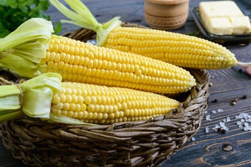 Raw sugar corn, sea salt, spices, herbs, butter on a dark wooden table. Close-up.