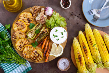 Grilled vegetables, fresh herbs, sauce on a wooden tray. Healthy food. A delicious appetizer. Top view.