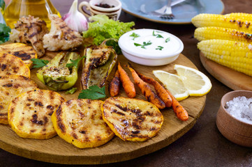 Grilled vegetables, fresh herbs, sauce on a wooden tray. Healthy food. A delicious appetizer.