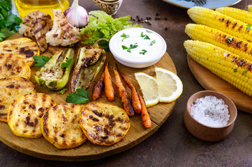 Grilled vegetables, fresh herbs, sauce on a wooden tray. Healthy food. A delicious appetizer.