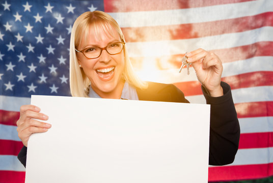 Young Woman Holding House Keys and Blank Sign In Front of American Flag
