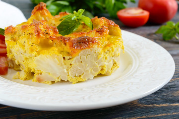 Tasty useful casserole from cauliflower on a plate on a dark wooden background. Vegetarian menu. Proper nutrition.