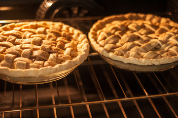 Two homemade apple pies baking in an oven on the top rack.  Horizontal image. © StudioStoltz