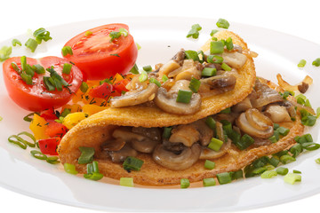 Omelet with mushrooms and tomatoes on a plate is decorated with onions. Isolated on white background.