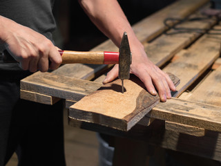 Fototapeta na wymiar A man is hammering a nail into a wooden board