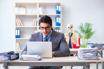 Businessman working with skeleton in office