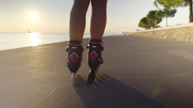Young caucasian woman roller skating in the sun, shot following legs, low angle close-up