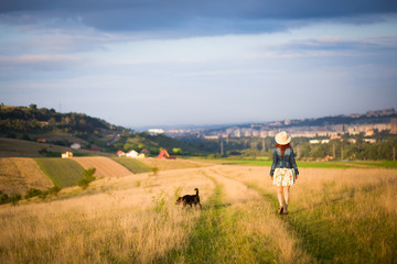 Girl walking in meadow with dog,summer holiday background
