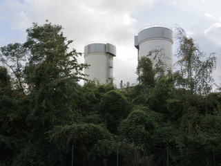 Industrial structures among green thickets near the road in clear weather