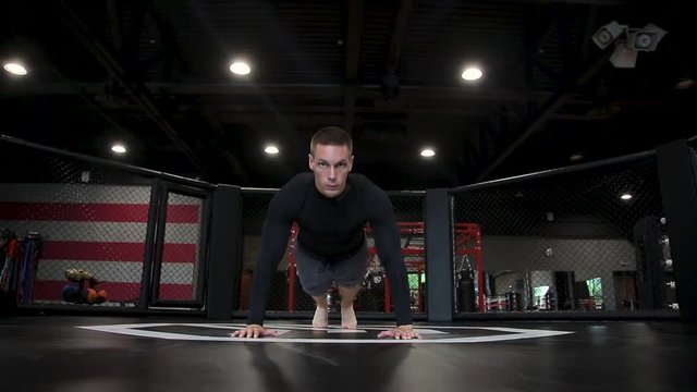 Man doing push-ups in gym, looking into camera