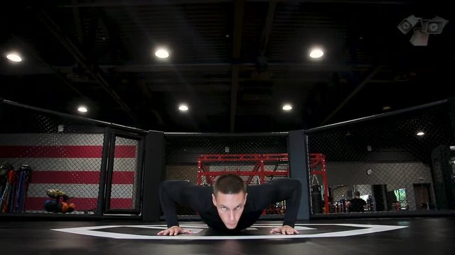 Man doing push-ups in gym, looking into camera